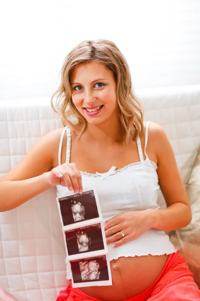 Привлекательная беременная женщина сидит на диване с эхом в руке — стоковое фото