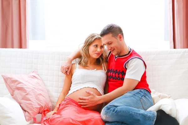 Счастливый молодой человек с беременной женой в животе — стоковое фото
