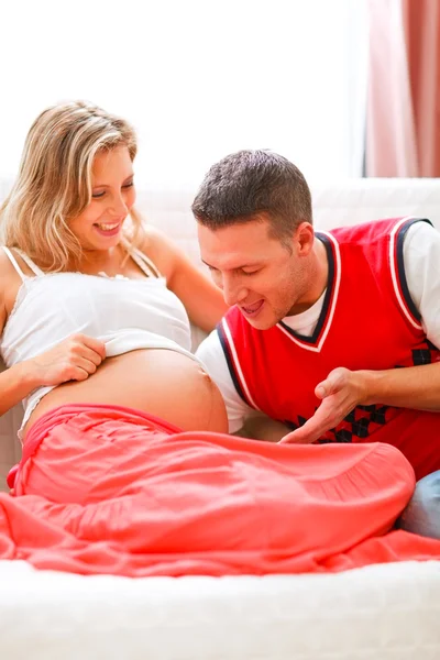 年轻的父亲在与他怀孕的妻子肚子说话 — 图库照片