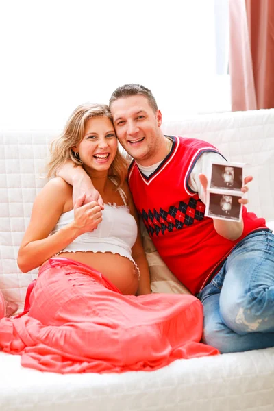 Lächelndes Paar zeigt das Sonogramm seines ungeborenen Kindes — Stockfoto