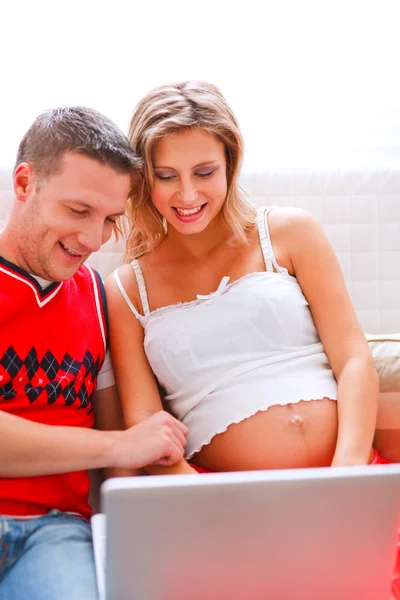 Feliz joven embarazada con marido trabajando en el ordenador portátil — Foto de Stock