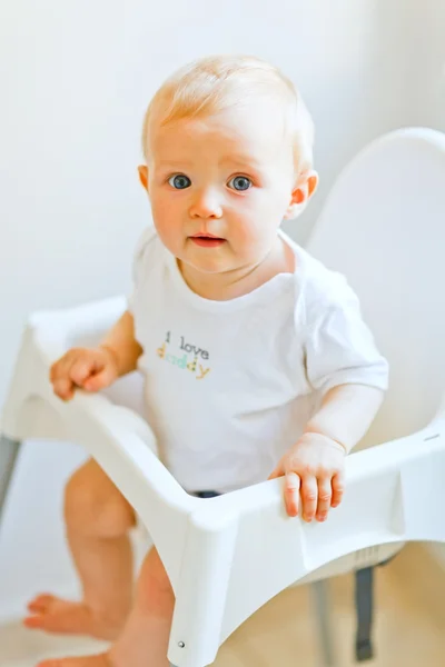 Linda menina sentada em cadeira de bebê — Fotografia de Stock