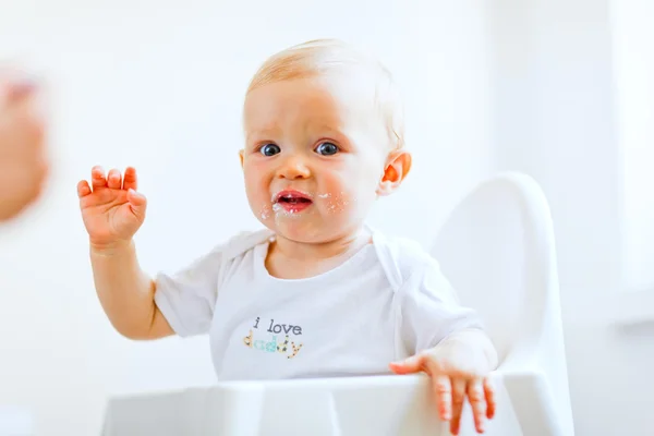Comer manchado bebê adorável em suspiros cadeira de bebê — Fotografia de Stock