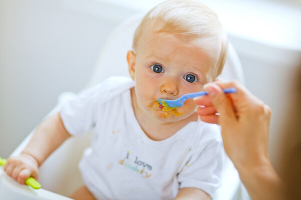 Eat smeared pretty baby eating from spoon