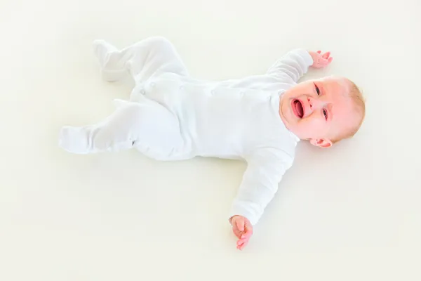 Crying four month old baby laying on back — Stock Photo, Image