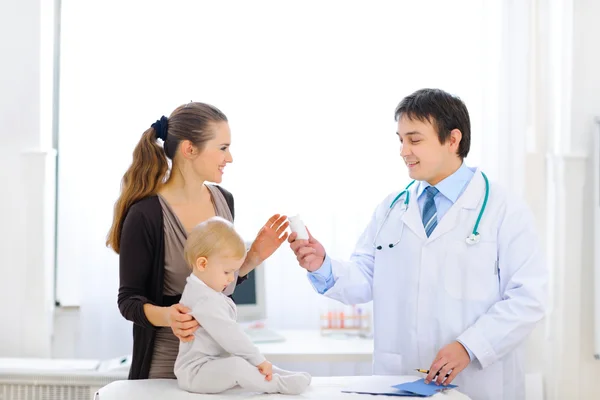 Pediatric doctor giving bottle of vitamins to mother Royalty Free Stock Images