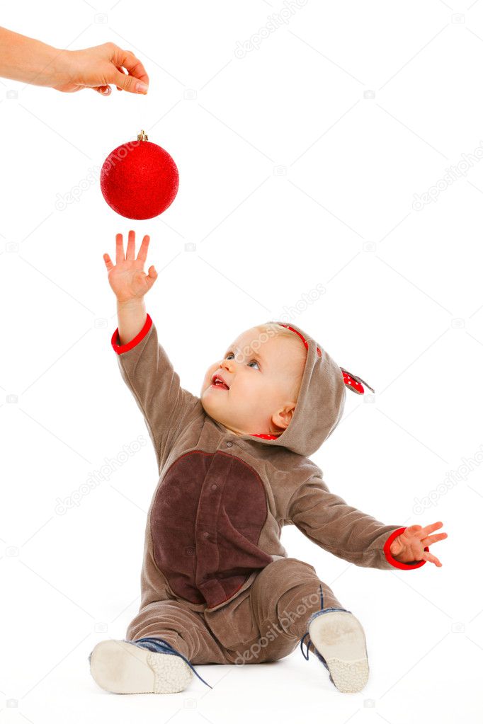 Cheerful baby playing stretching hand to Christmas ball