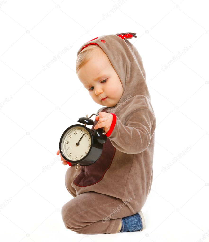 Adorable baby in costume of Santa Claus reindeer with alarm clock