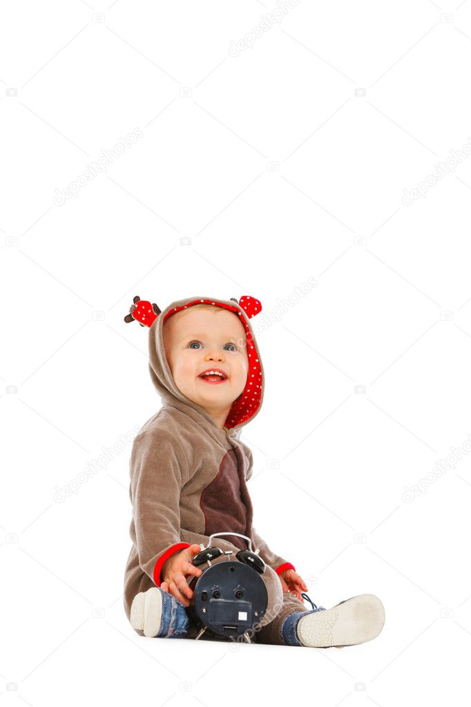 Baby in costume of Santa Claus's reindeer with alarm clock looki