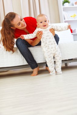 neşeli bebek yürümeyi öğrenmek yardımcı gülümseyen anne