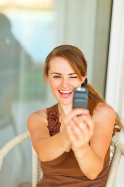 Smiling beautiful woman taking photo of herself on mobile phone clipart