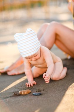 Little baby playing with sand on beach clipart