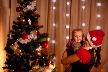 Portrait of adorable baby on mamas hand near Christmas tree clipart