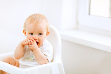 Lovely baby sitting in baby chair clipart