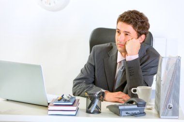 Bored modern businessman sitting at office desk clipart