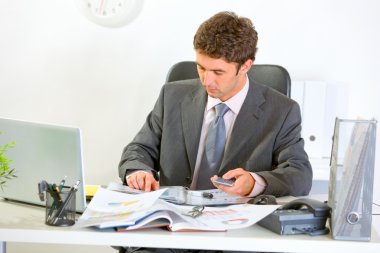 Confident modern businessman working with documents clipart