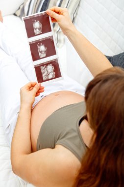 Pregnant woman relaxing on couch and looking echo. Close-up. clipart