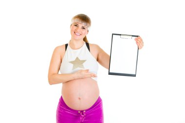 Smiling beautiful pregnant woman pointing on blank clipboard clipart