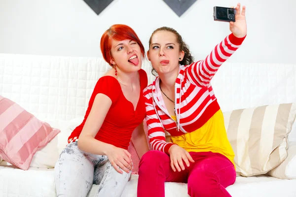 Lustige Freundinnen, die Zunge zeigen, während sie sich selbst fotografieren — Stockfoto