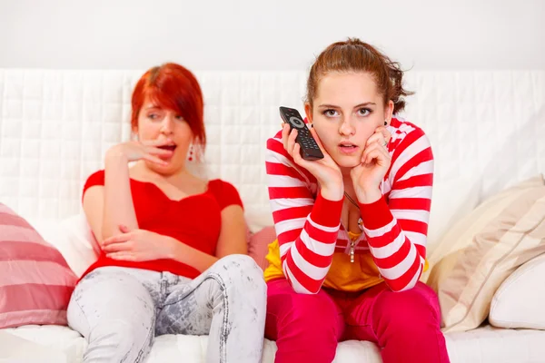 Gelangweiltes Mädchen gähnt, während ihre Freundin aufmerksam fernsieht — Stockfoto