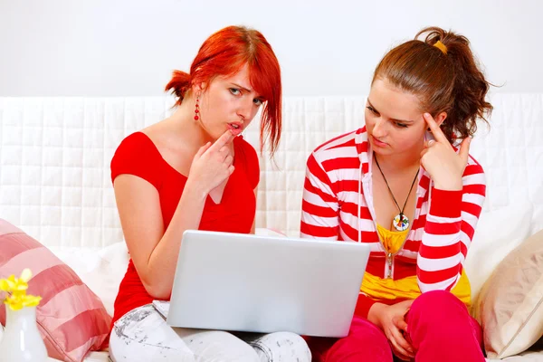 Bewildered girlfriends looking in laptops screen — Stock Photo, Image