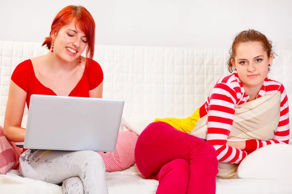 Pretty girl bored while her girlfriend using laptop — Stock Photo, Image