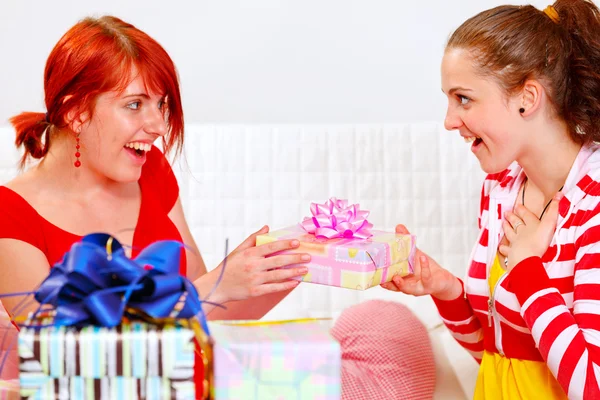 Pretty girl presenting gift to her girlfriends — Stock Photo, Image