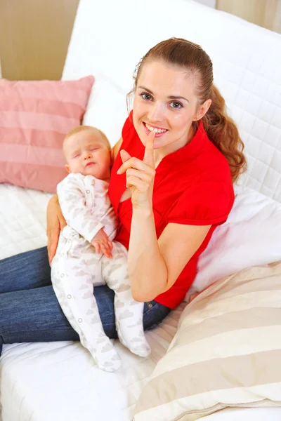 Feliz madre sosteniendo bebé dormido y mostrando gesto shhh — Foto de Stock