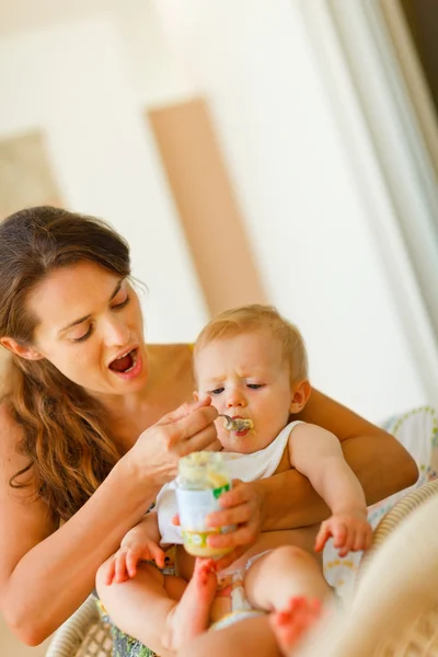 Jovem mamãe alimentando pequeno bebê — Fotografia de Stock