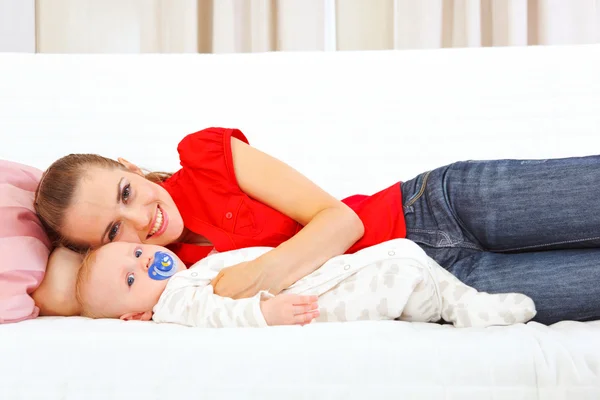 Sorrindo mãe e bebê deitado no sofá — Fotografia de Stock