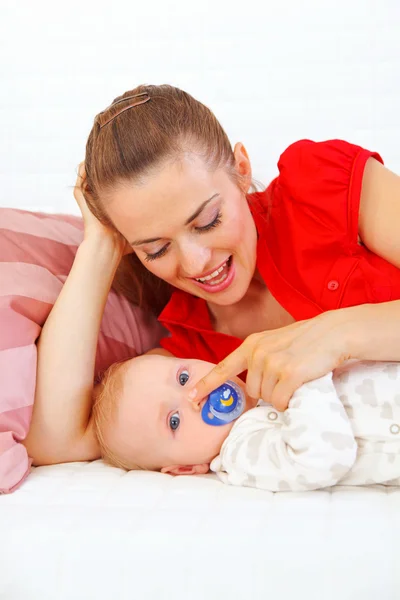 Kanepede döşenmesi ve bebekle oynayan genç anne — Stok fotoğraf