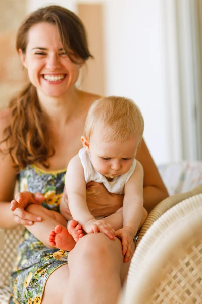 Dizlerinin üstüne oturan bebek ile anne gülerek — Stok fotoğraf