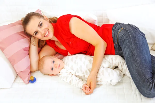 Happy mother and baby laying on sofa — Stock Photo, Image