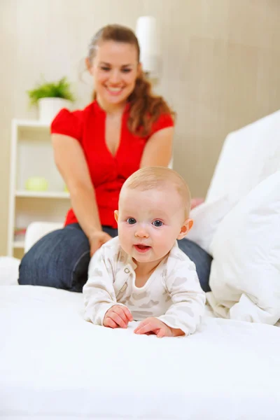 Smiling mother and adorable baby playing on sofa — Stock Photo, Image