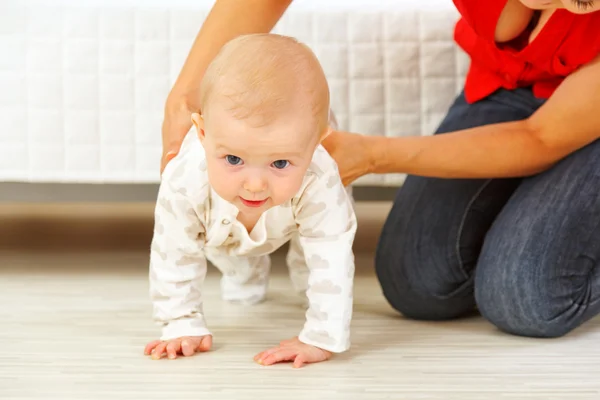 Mother helping cheerful baby learn to creep — Stock Photo, Image