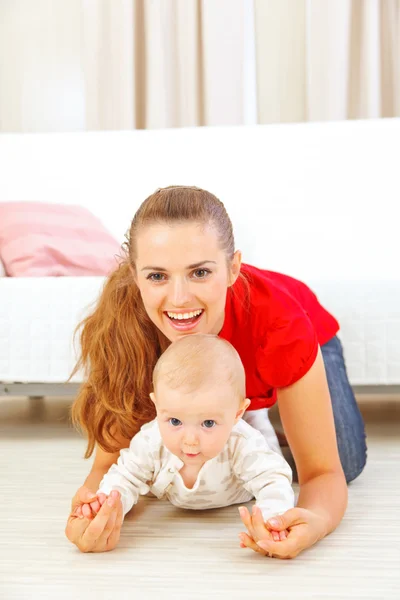Sorrindo mamãe e adorável bebê brincando no chão — Fotografia de Stock
