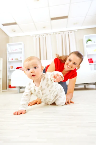 Улыбающаяся мама играет с ползающим по полу младенцем — стоковое фото