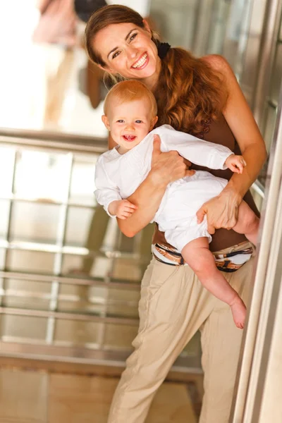 Retrato de madre sonriente con bebé mirando desde el ascensor — Foto de Stock