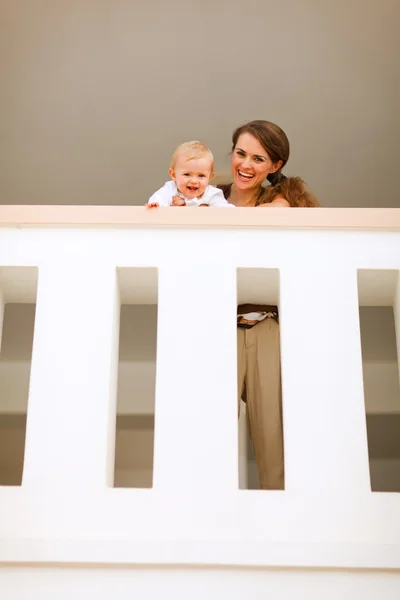 Portrait of mother with happy baby looking down from railing — Stock Photo, Image