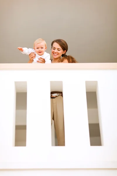 Portret van moeder met gelukkig baby naar beneden te kijken van reling — Stockfoto