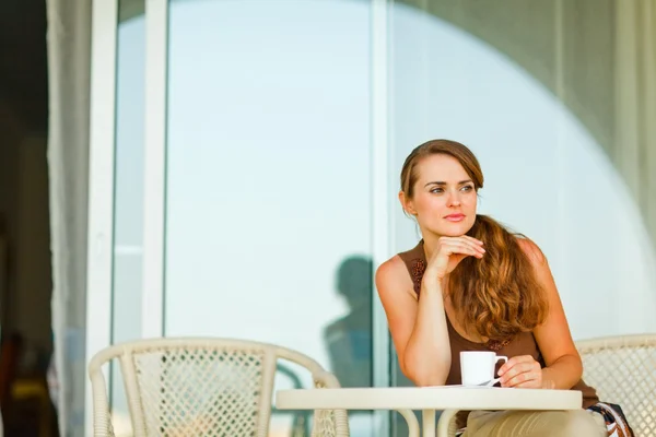 Mulher atenciosa sentada no terraço e tomando uma xícara de café — Fotografia de Stock
