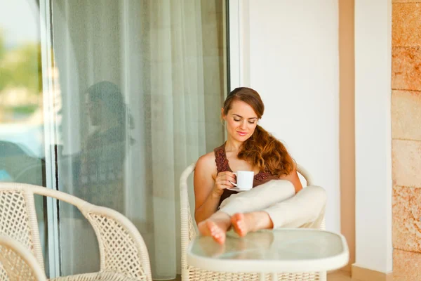 Ηρεμήσει το χαλαρωτικό όμορφη γυναίκα στη βεράντα με το φλυτζάνι του καφέ — Φωτογραφία Αρχείου