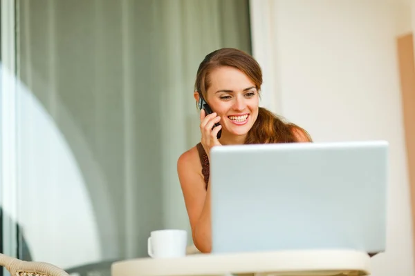 Mujer joven sonriente en la terraza hablando teléfono celular y mirando o — Foto de Stock