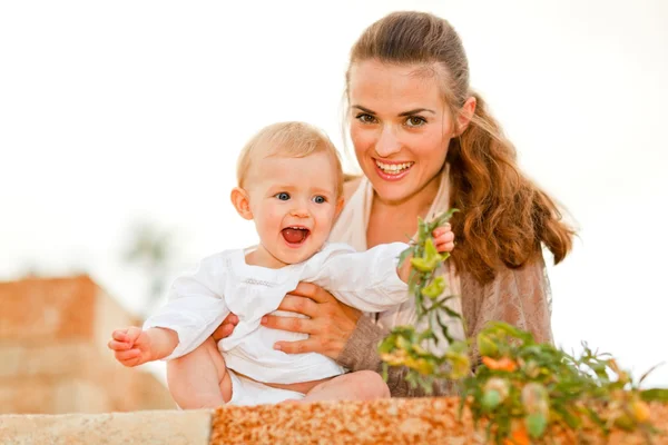 Портрет счастливой матери и смеющегося ребенка, играющего с растениями — стоковое фото