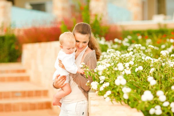 Mère attentionnée montrant des plantes à son bébé intéressé — Photo