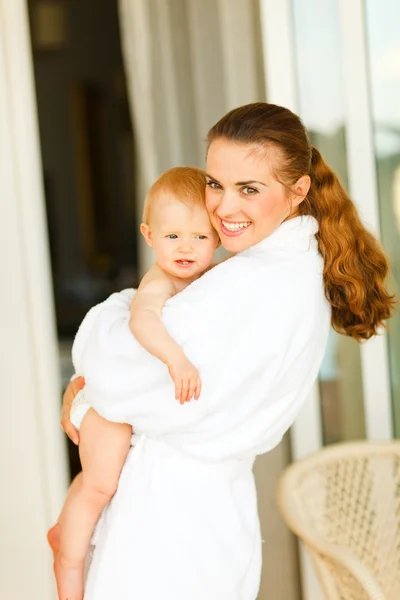 Retrato de madre joven en albornoz con bebé en la mano — Foto de Stock