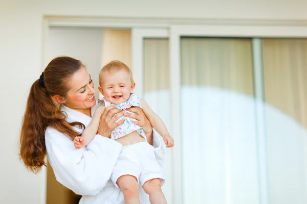 Ung mamma i badrock med lycklig bebis i handen — Stockfoto