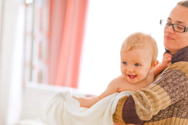 Cheerful baby on mamas arms looking in corner — Stock Photo, Image