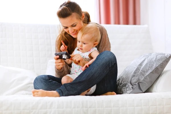 Young mom showing her interested baby photos on camera — Stock Photo, Image