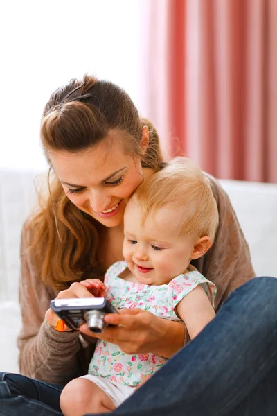 Young mother showing her smiling baby photos on camera — Stock Photo, Image